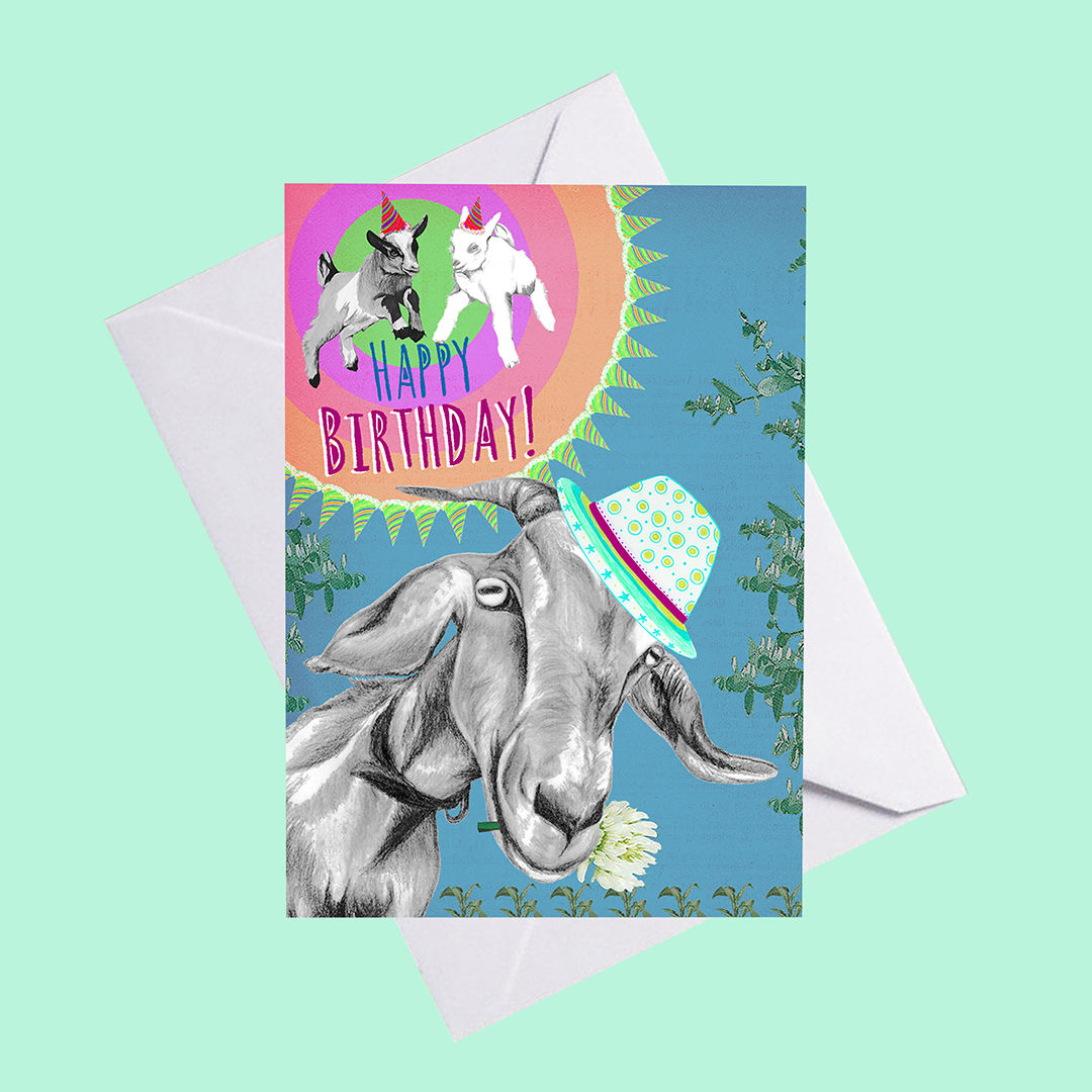 An illustrated blue collaged birthday greeting card of a goat. The card rests on a white envelope and mint background.