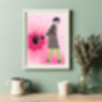 A pink and bold patterned fashion art print, displayed in a white frame on an olive green wall, above a shelf with plants.