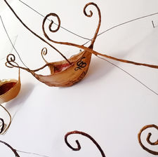 Particolare dell'installazione artistica Love Boat per Ek Ong Kar. L'installazione è formata da un insieme di sculture che rappresentano barche stilizzate di ferro e carta dipinta color rame antichizzato, l'interno dello scafo è rosso e sulla prua della barca centrale è visibile l'ideogramma ek ong kar dipinto in nero.