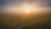 Wide-angle view of sunlight breaking through clouds over a peaceful field.