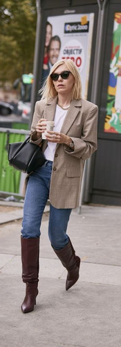 Woman of colour wearing knee high boots a blazer and jeans