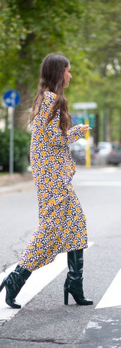 Woman wearing a colourful maxi dress with knee high boots.
