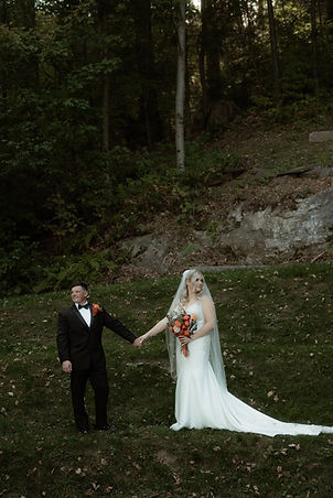 Cinemati wide shot of a bride and groom holding hands while looking across the fields at Retreat Farm in Brattleboro, Vermont