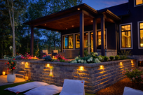Lit patio and landscaped yard at night, ideal site improvement.