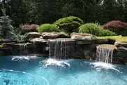 Rock waterfall cascading into a blue swimming pool