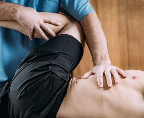 Therapist examines patient's leg, demonstrating physical therapy techniques on wooden background.