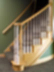 Wood staircase with decorative iron balusters and natural-finish wood railing, combining traditional craftsmanship with modern detail.