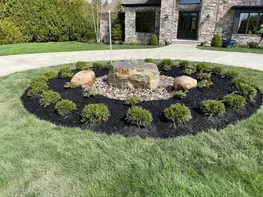 Circular landscape bed with rocks and shrubs