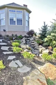 Landscaped hillside with stone steps and water feature