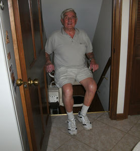 Senior man using a chair from local stairlift installation companies.