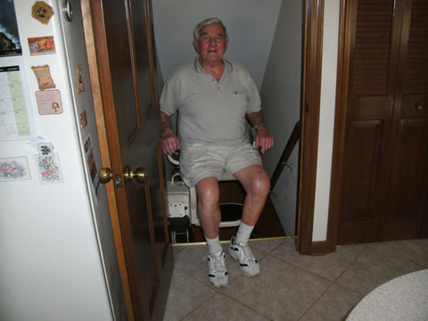 Senior man using a chair from local stairlift installation companies.