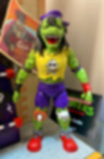 NECA's Archie Mondo Gecko revealed at 2023 SDCC. A mutant rock and roll hair band lizard with a skull and crossbone yellow shirt, braces, stoner eyes, ripped sleeves and ripped purple shorts