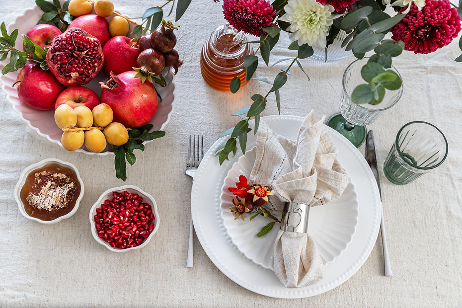 Jewish holiday Rosh Hashana festive table setting with plate, honey, apple ,pomegranates,