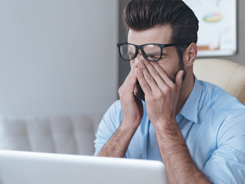 Uomo che sfrega gli occhi davanti ad un pc, affaticamento visivo, luce blu dispositivi elettronici 