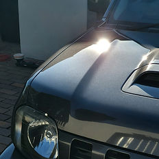 Front of a dark car with sun glare on the hood
