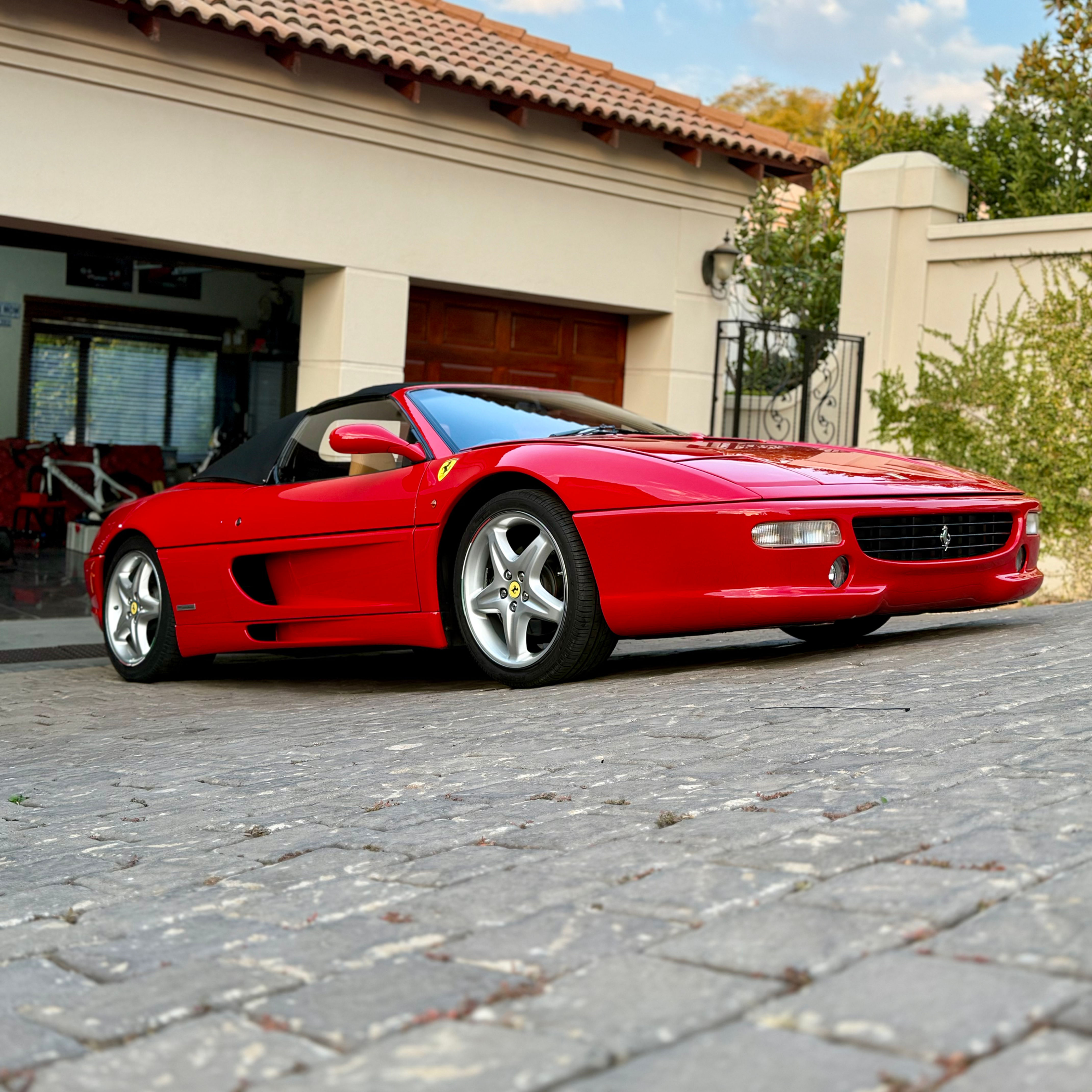 Red Ferrari sports car parked outside a garage.