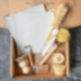 Eco-friendly cleaning kit with wooden brushes and white cloths in a cardboard box. Green text reads "Thank you for being awesome."
