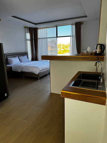 Køkkenområde med vask og udsigt til soveværelset i en gul hytte.