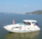 A woman sipping champagne while standing on the sundeck of a luxury yacht in Goa with a large bridge in the background