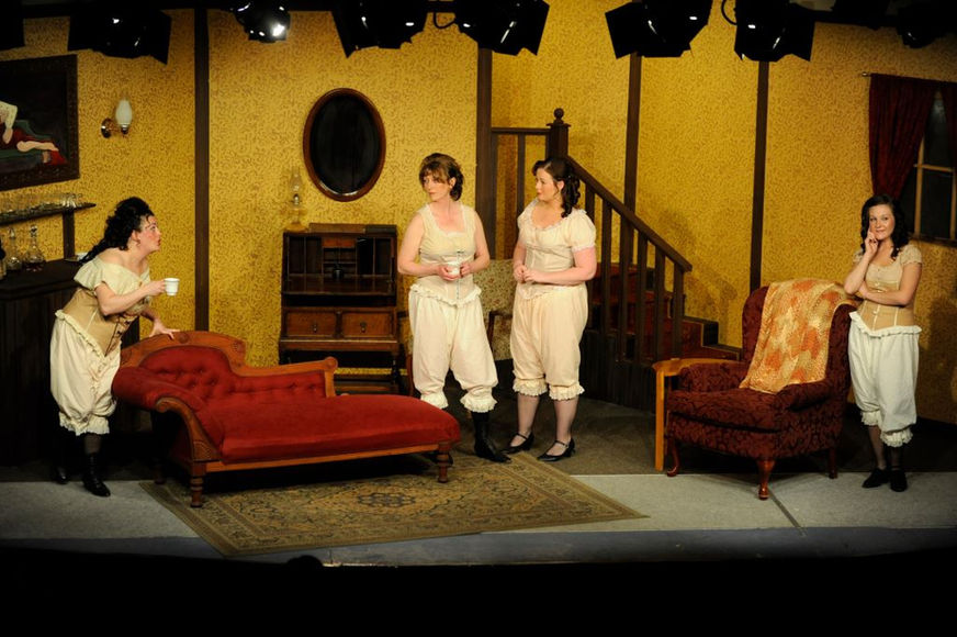 Four women on stage, in vintage clothing, preparing for a play performance. What's On Stage