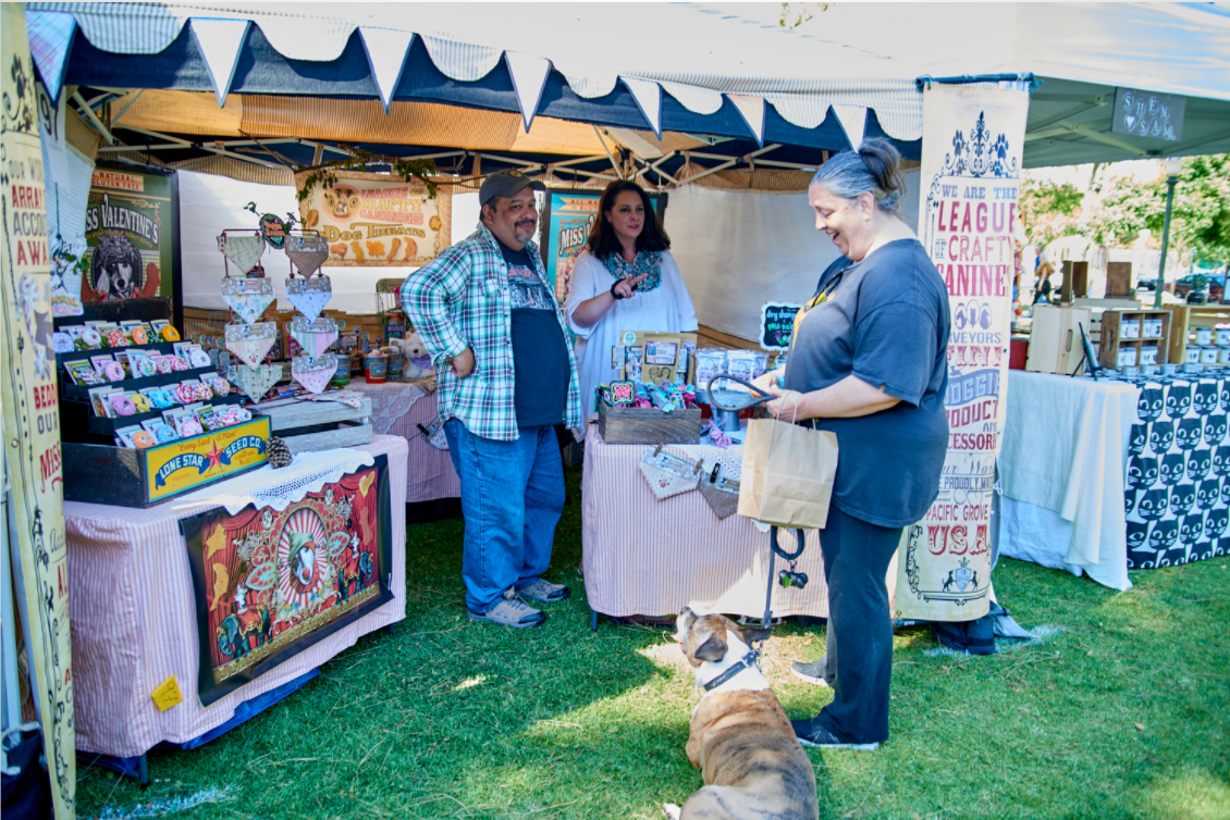 People at a craft booth with dog treats and accessories. Circus themed booth aligns with their branding.