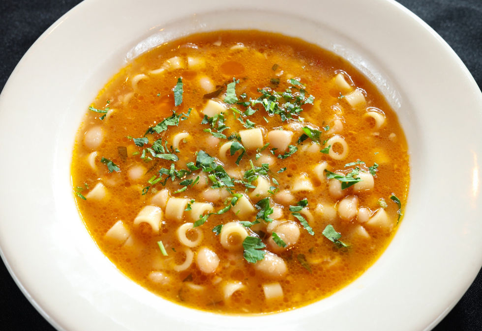 Minestrone soup with pasta and beans, topped with parsley.