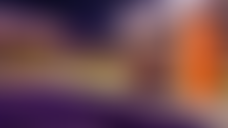 Football rests beside an orange goal-line pylon in a purple-and-gold night stadium