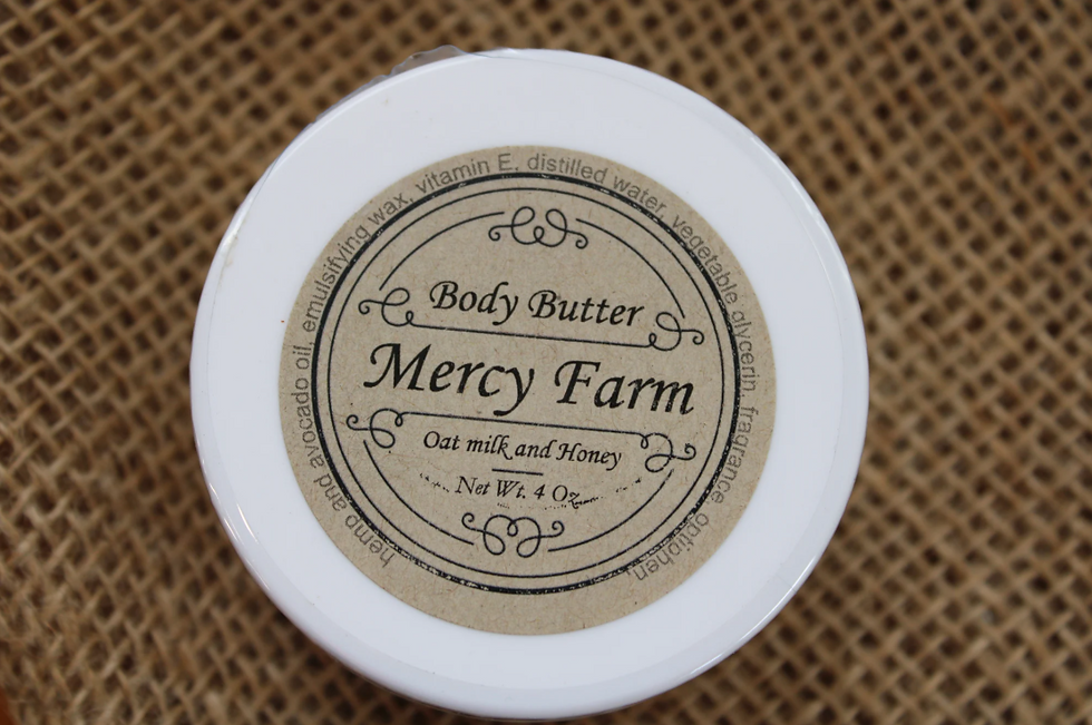 Mercy Farm Body Butter (Oat Milk & Honey) in a white jar with vintage label on burlap background.
