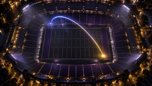 Aerial night stadium with a blue-and-gold trajectory arc landing near the corner inside the 10-yard line
