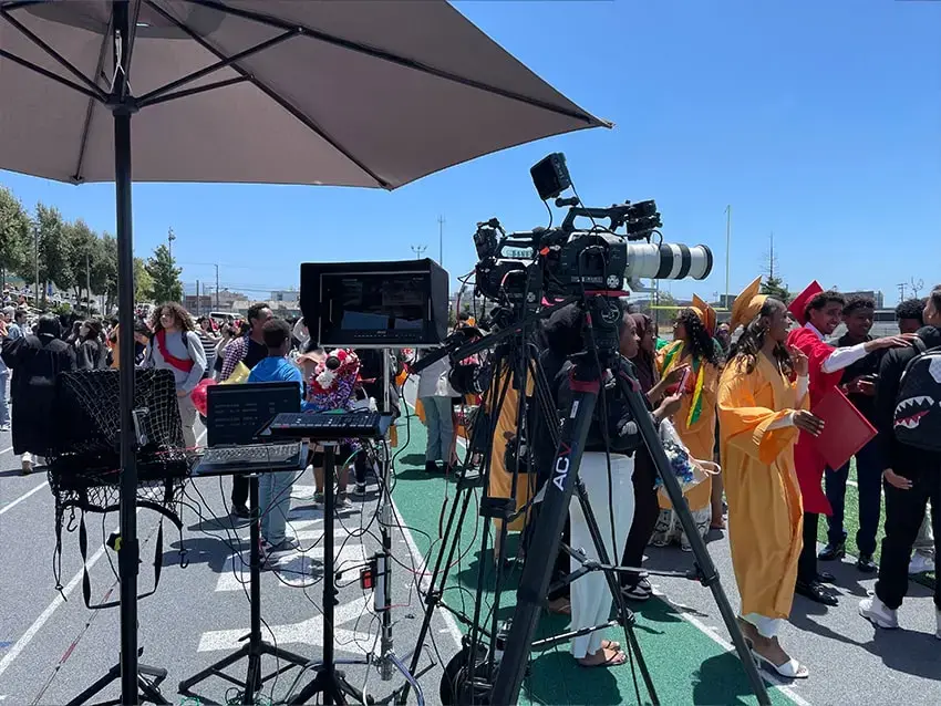Outdoor graduation live streaming setup with professional camera, monitor, and audio equipment