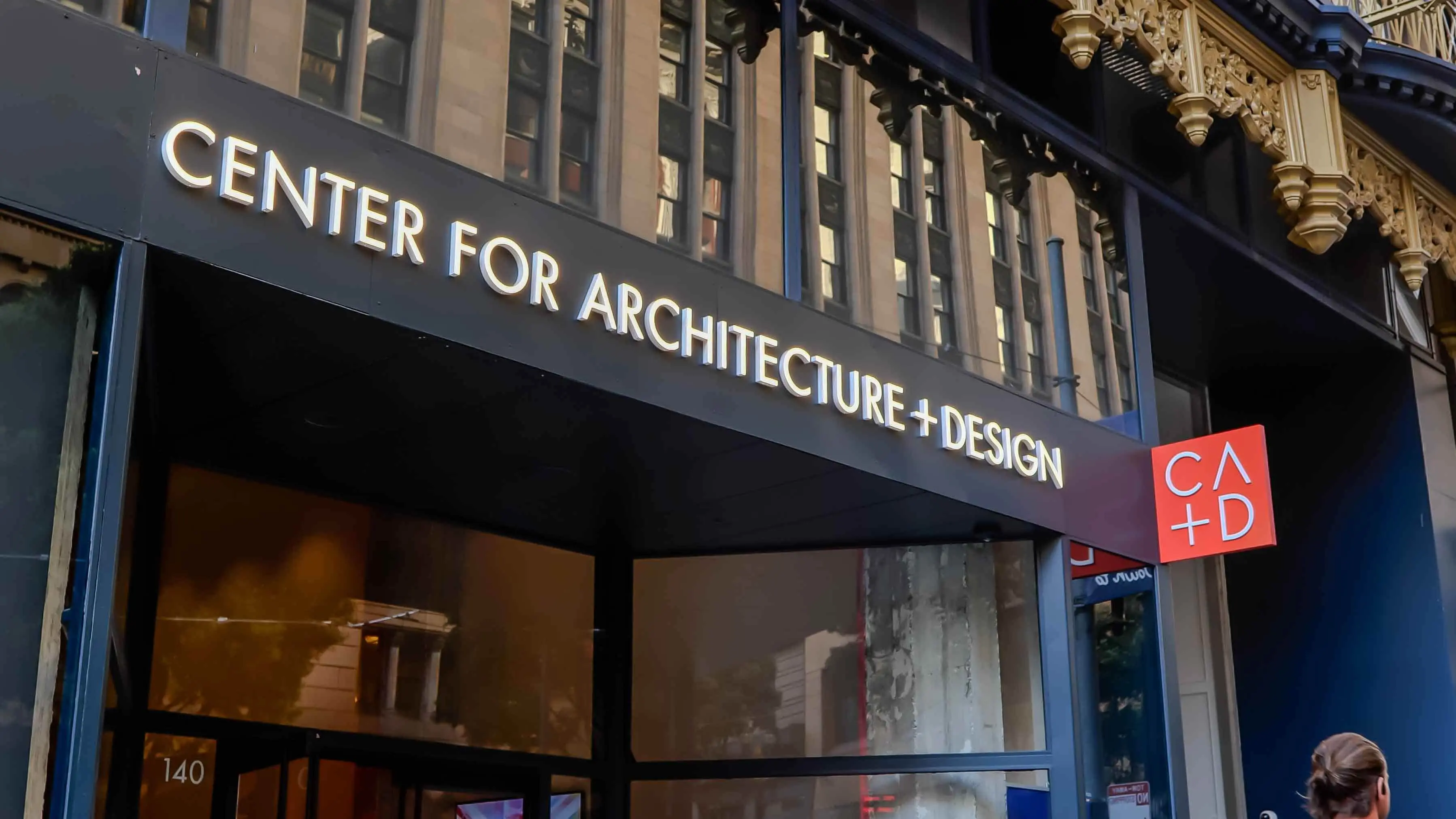 Close-up of the entrance signage at the Center for Architecture + Design in San Francisco, featuring the CA+D logo and modern glass facade.