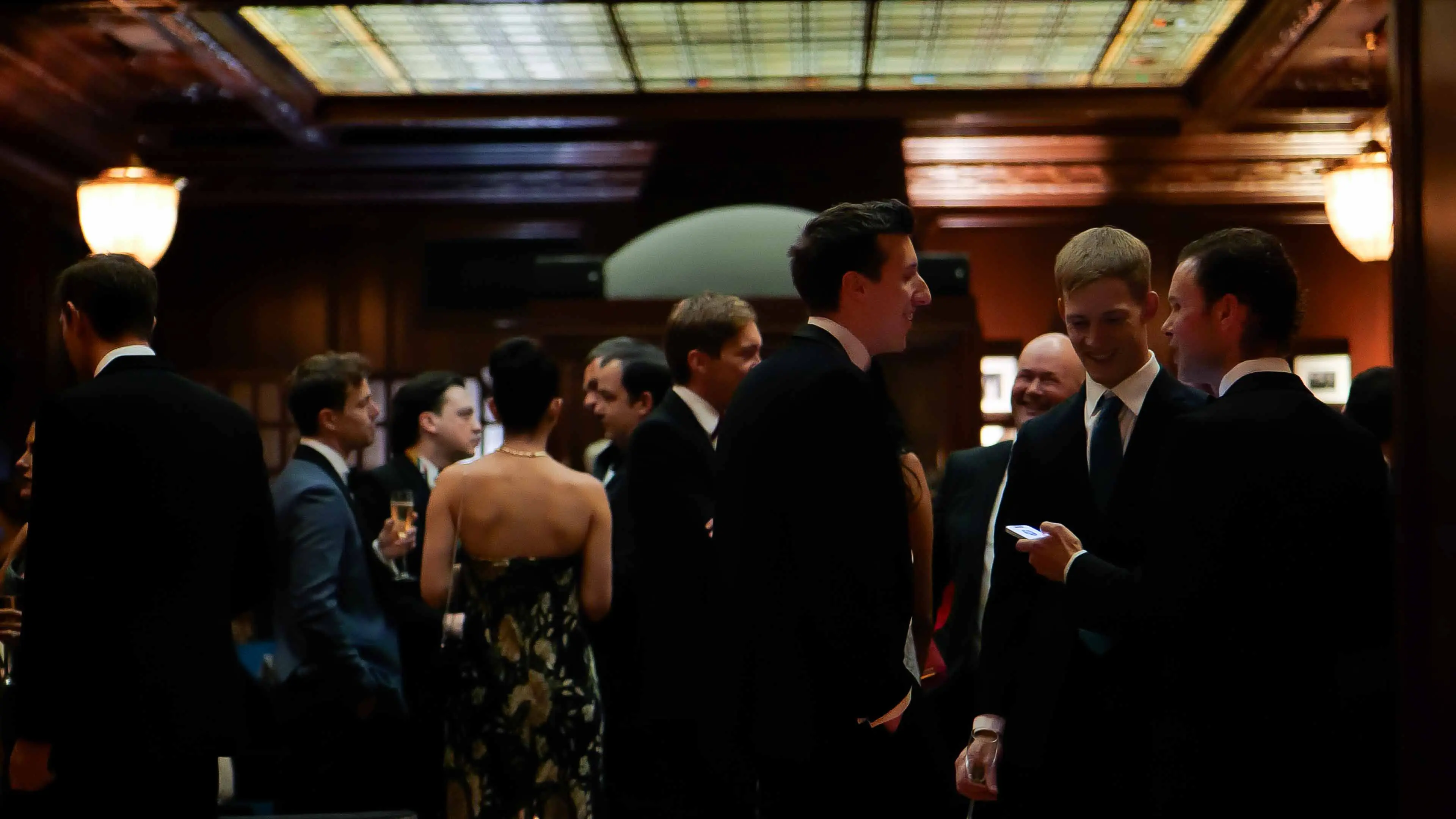 Attendees networking in formalwear during the GREAT GBx Gala 2024 at the Palace Hotel in San Francisco, gathered beneath a stained glass ceiling in the historic venue.
