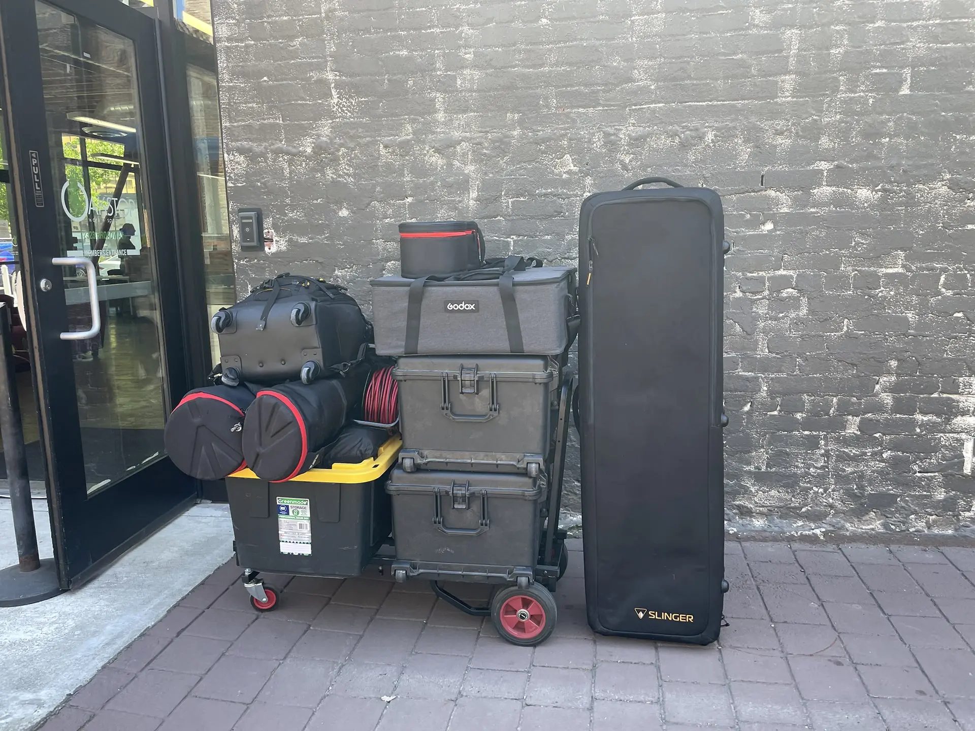 Video production gear loaded on carts outside Oakstop in Oakland, ready for setup at the Black Political Power Tour – including lighting cases, tripods, and audio equipment.