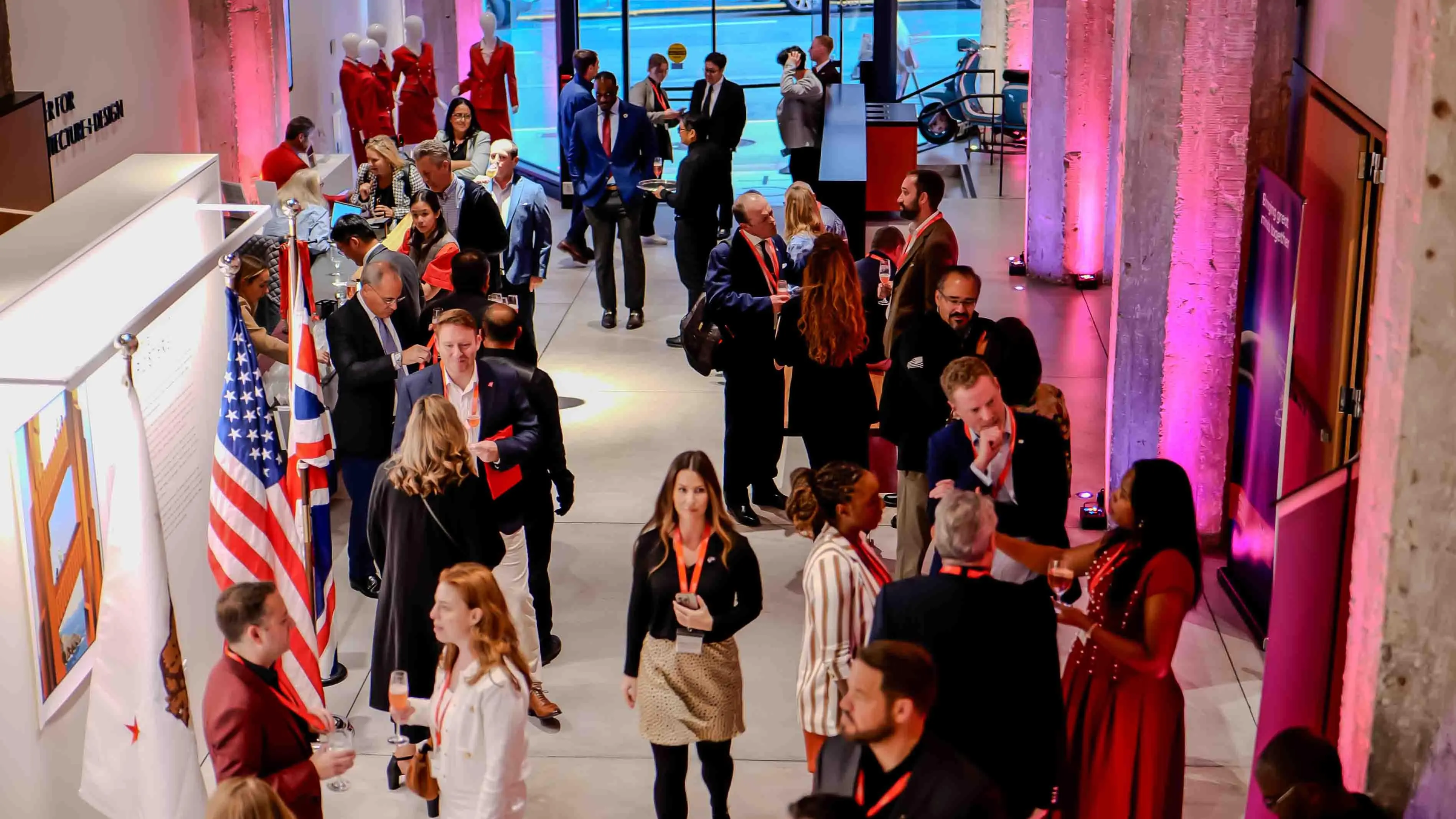 Guests networking at the Virgin Atlantic and British Consulate 30-year celebration event in San Francisco, held at the Center for Architecture + Design, with ambient lighting and international flags on display.
