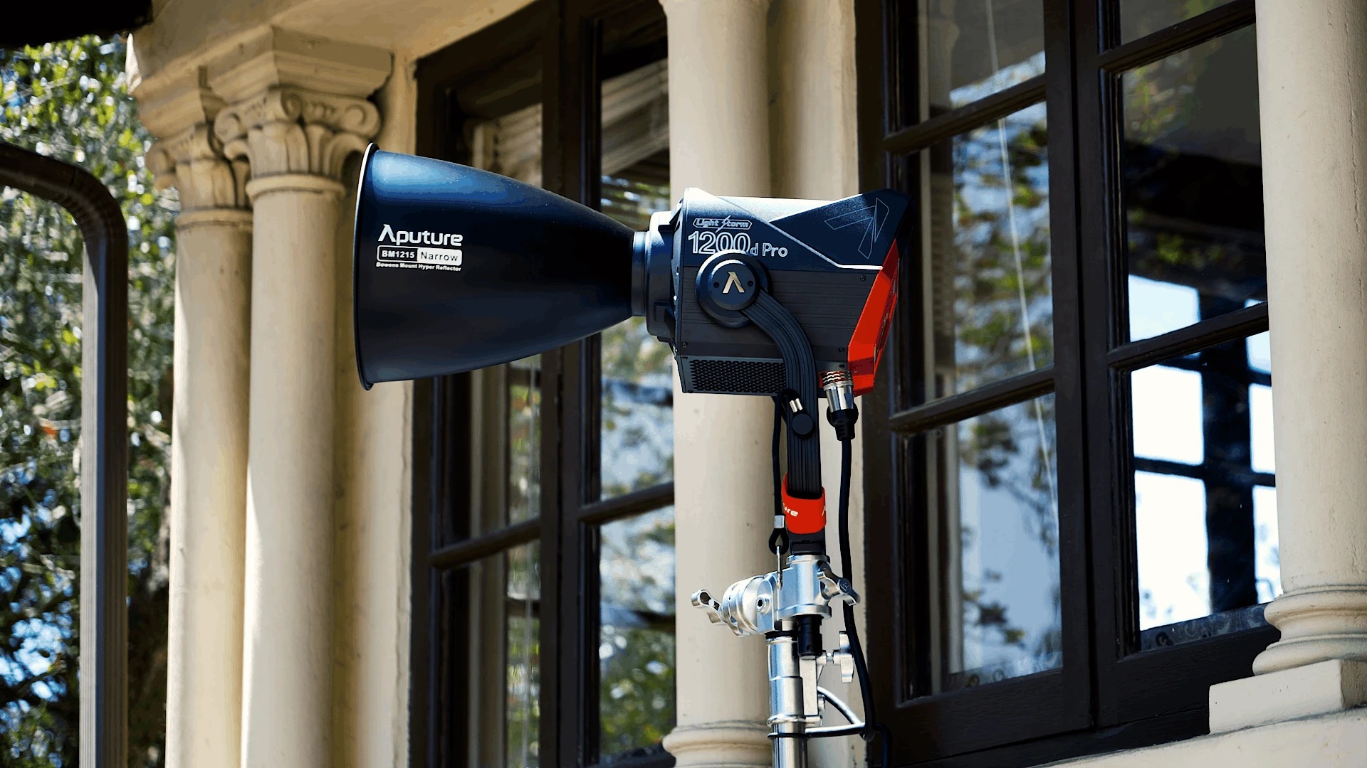Aputure 1200D light on a stand used to brighten an outdoor commencement stage where tall trees created deep shade.
