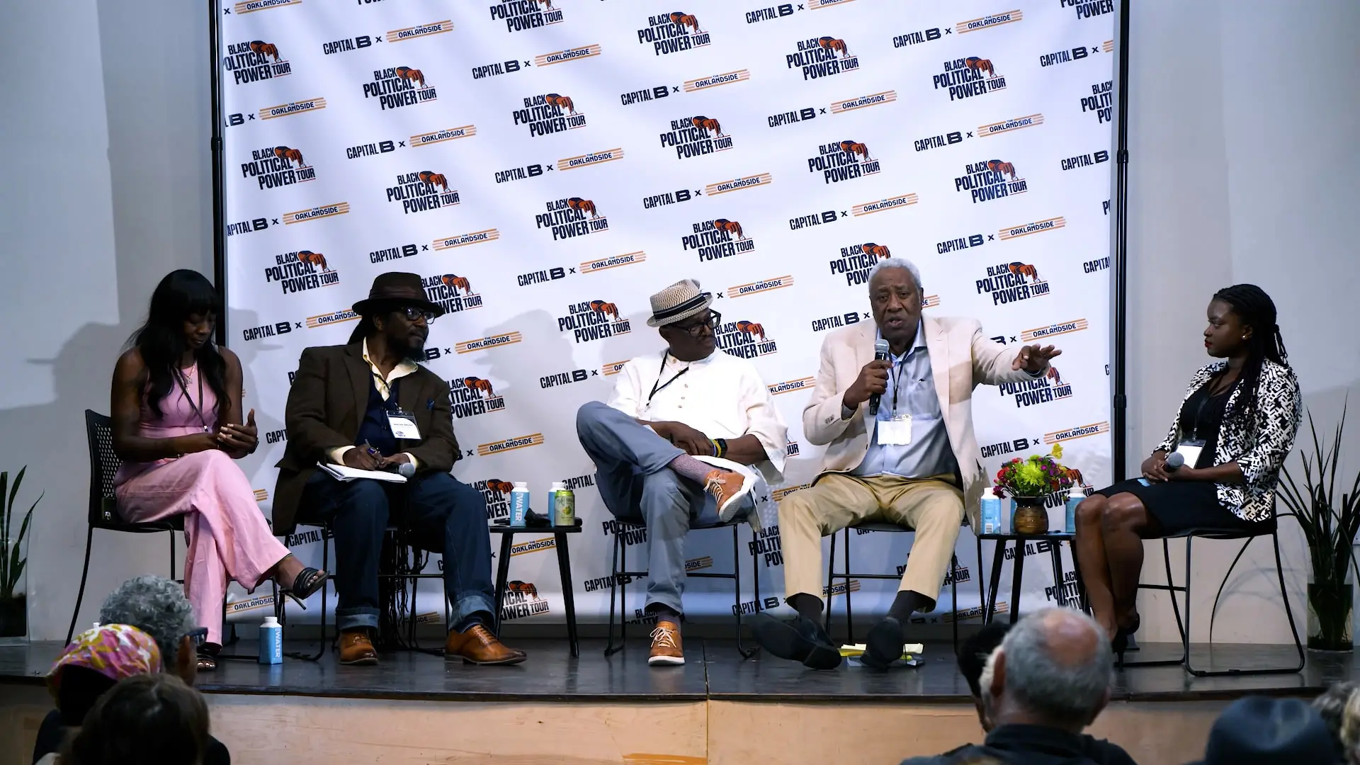 Speakers engaged in a lively panel discussion at the Black Political Power Tour – Oakland, seated on stage with branded backdrop featuring Capital B and event logos.