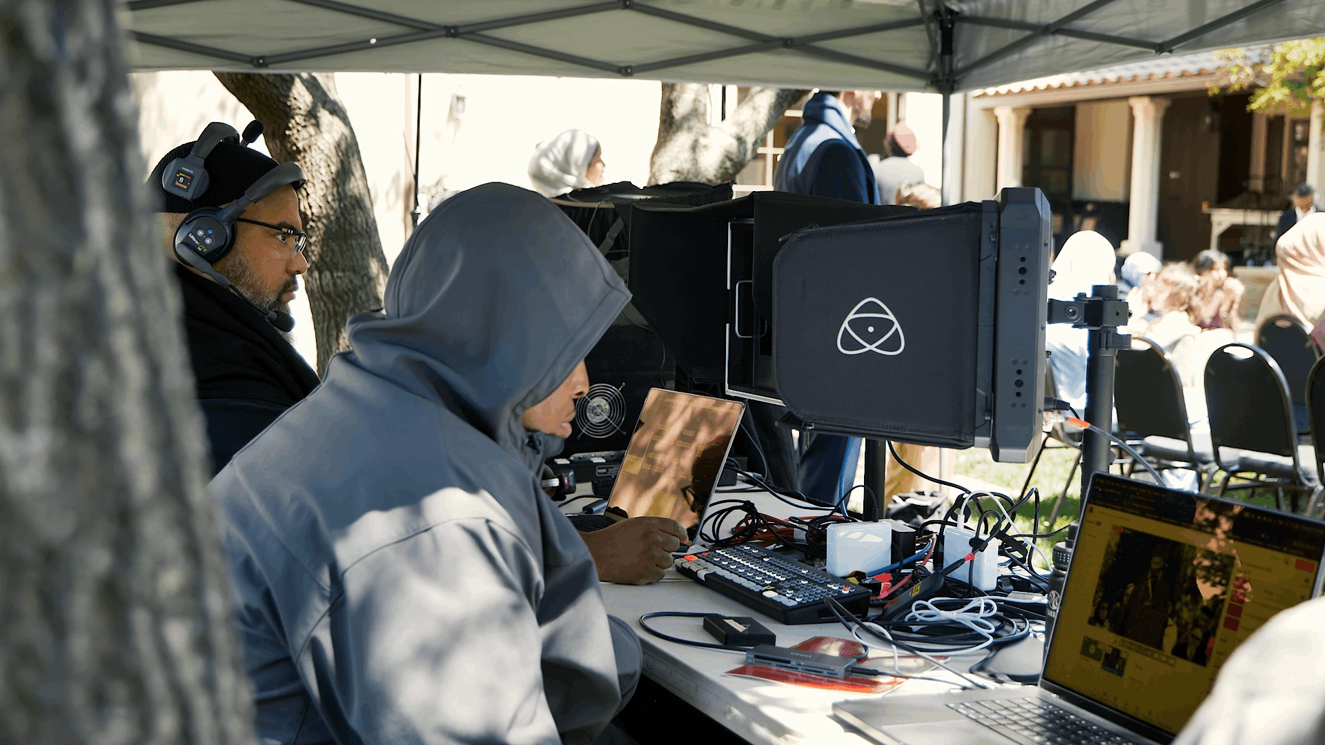 Live stream switching desk under a canopy with monitors and an ATEM-style control setup, operated outdoors during a commencement ceremony in Berkeley, CA