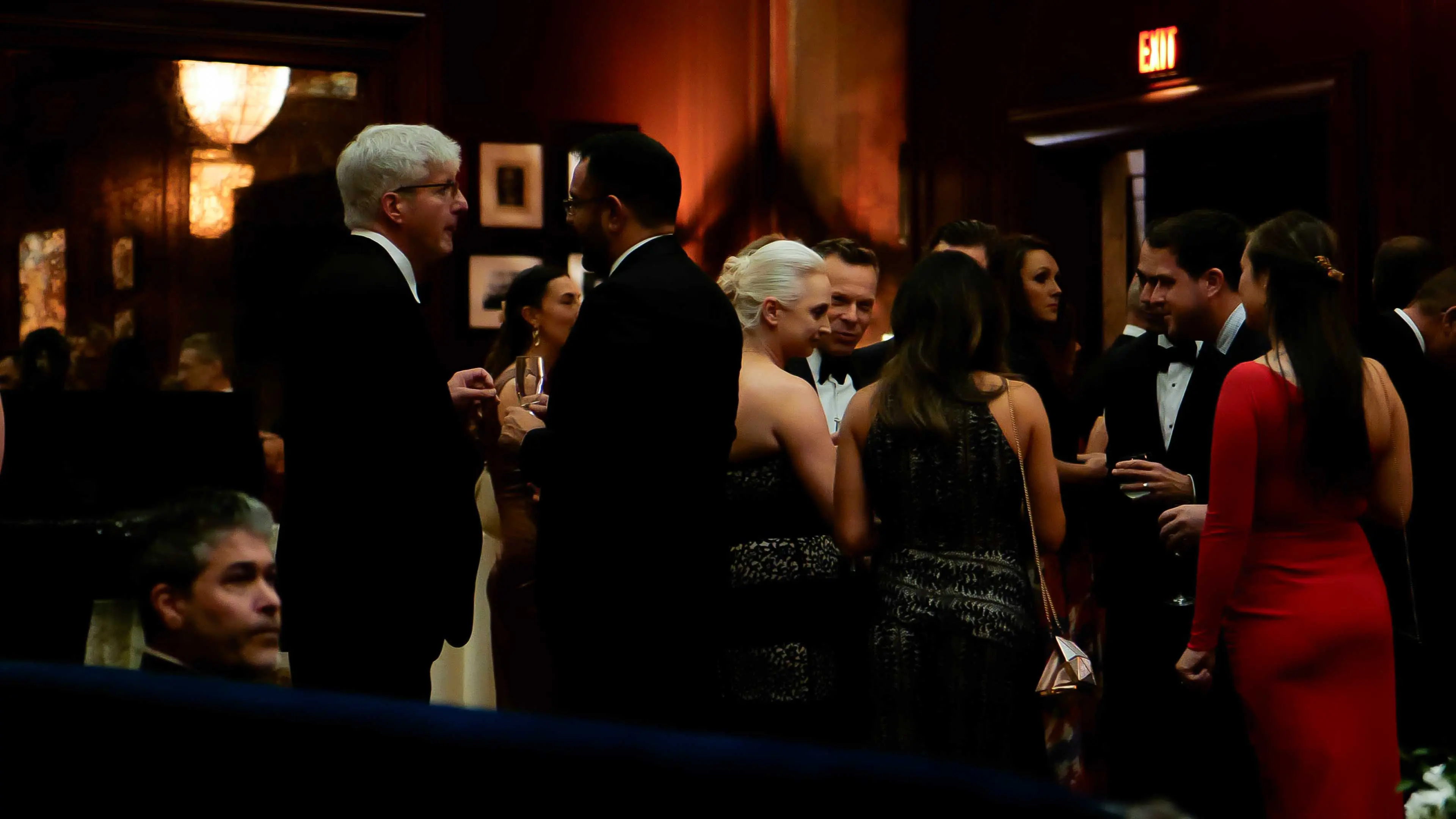 Guests in formal evening attire socializing and enjoying drinks in a dimly lit reception room during the GREAT GBx Gala 2024 at the Palace Hotel in San Francisco.