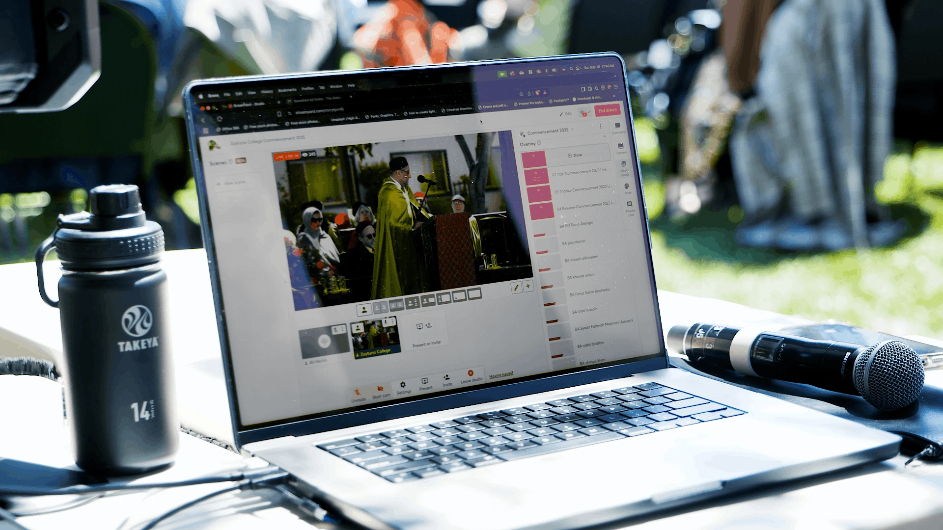 Laptop at a commencement live stream station showing the streaming dashboard and video preview, with production gear visible nearby.