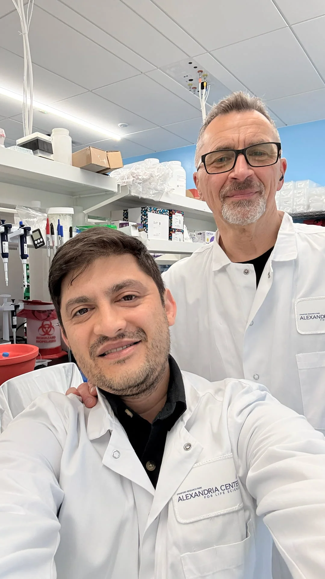 Saboor Bidar with a Alan Cash in a lab, wearing lab coats during a training video production shoot for Portal Therapeutics.