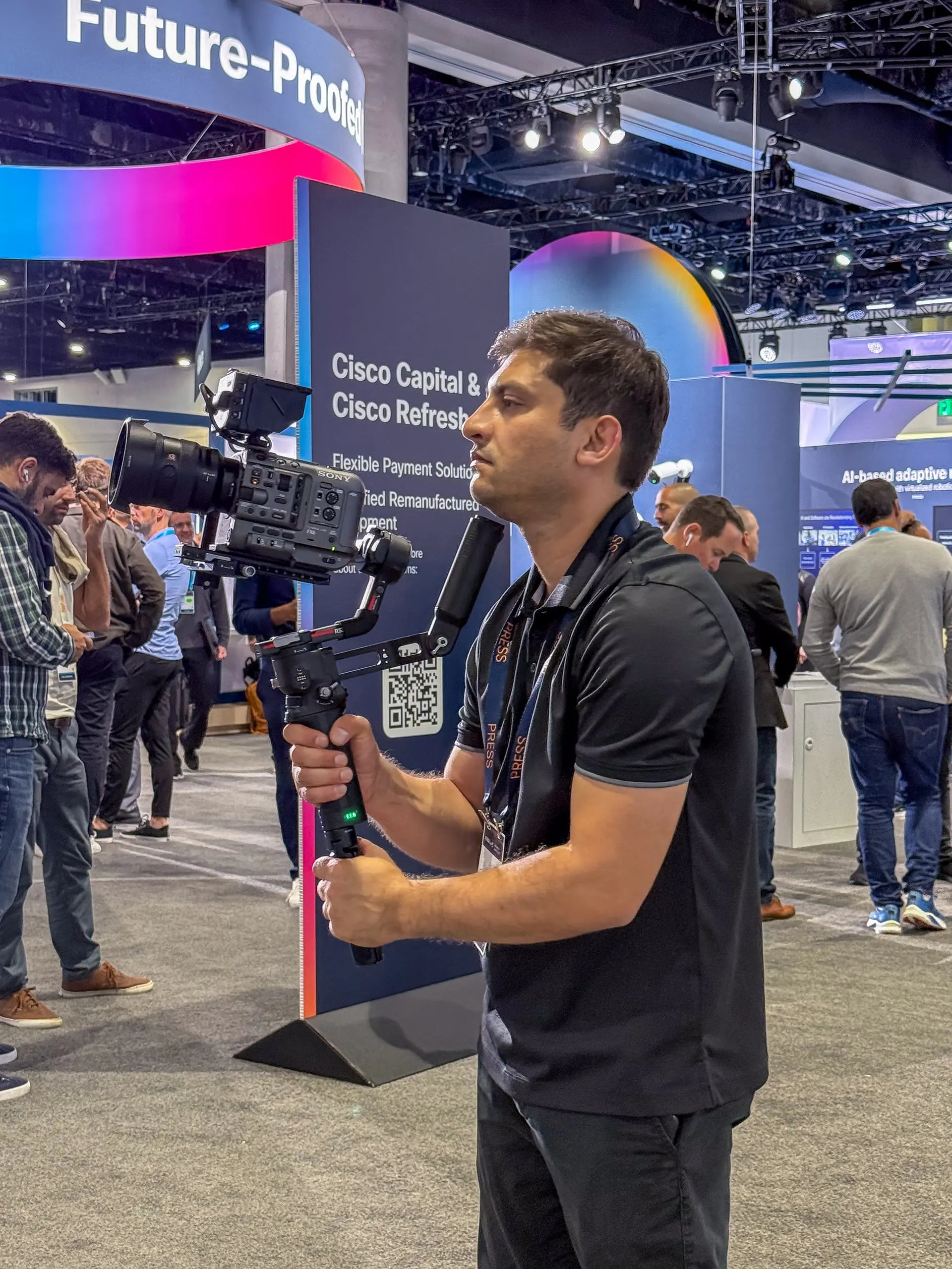 Saboor Bidar at FMS 2025 in Santa Clara Convention Center holding a Sony FX6 camera on a DJI RS3 Pro gimbal, capturing cinematic B-roll for Dapustor’s trade show booth videography