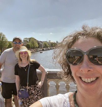 A selfie taken by Inbal Tur-Shalom while guiding a tourist couple in Amsterdam, with the Amstel River in the background.