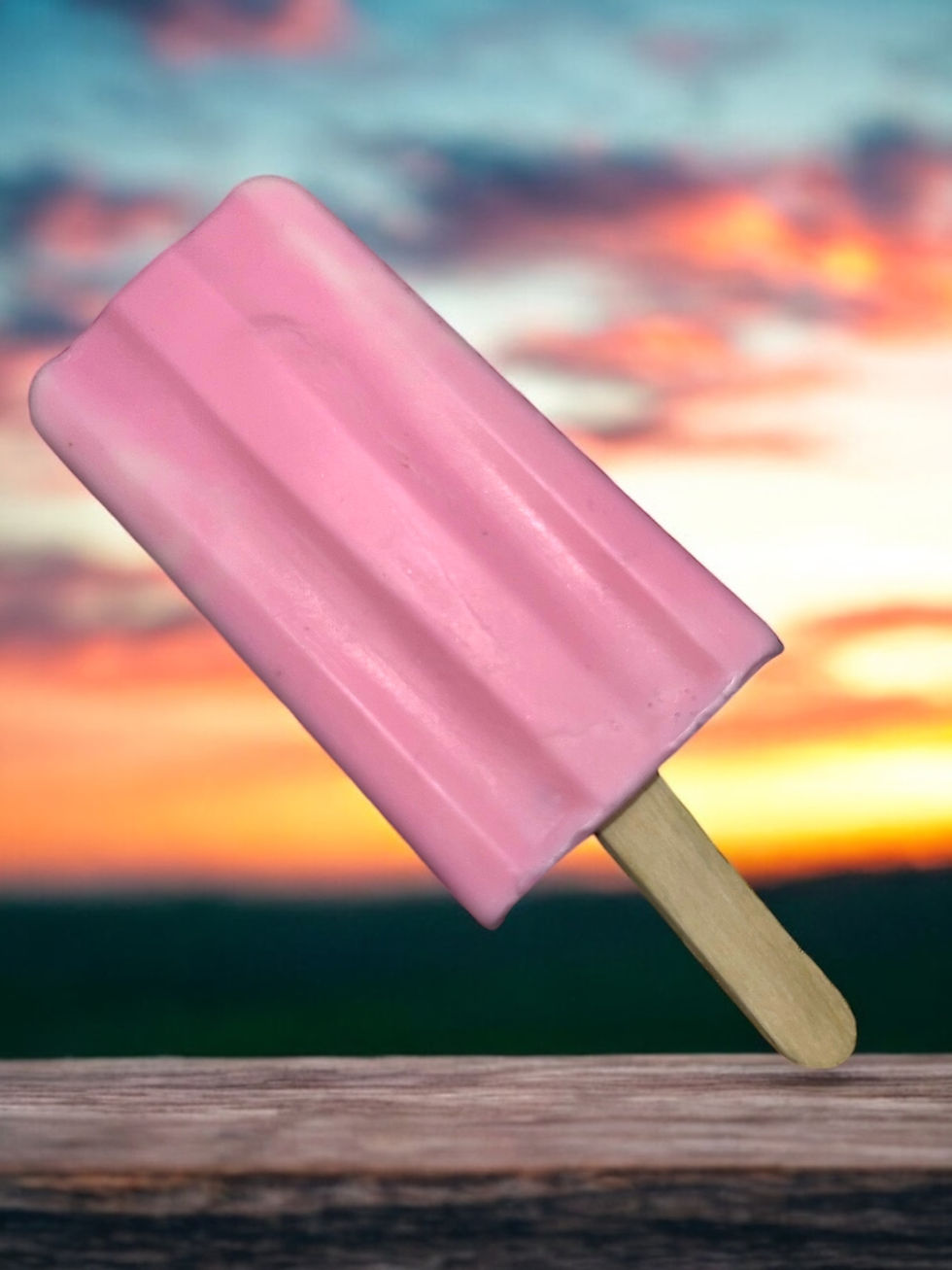 Pink popsicle on wooden stick, sunset background