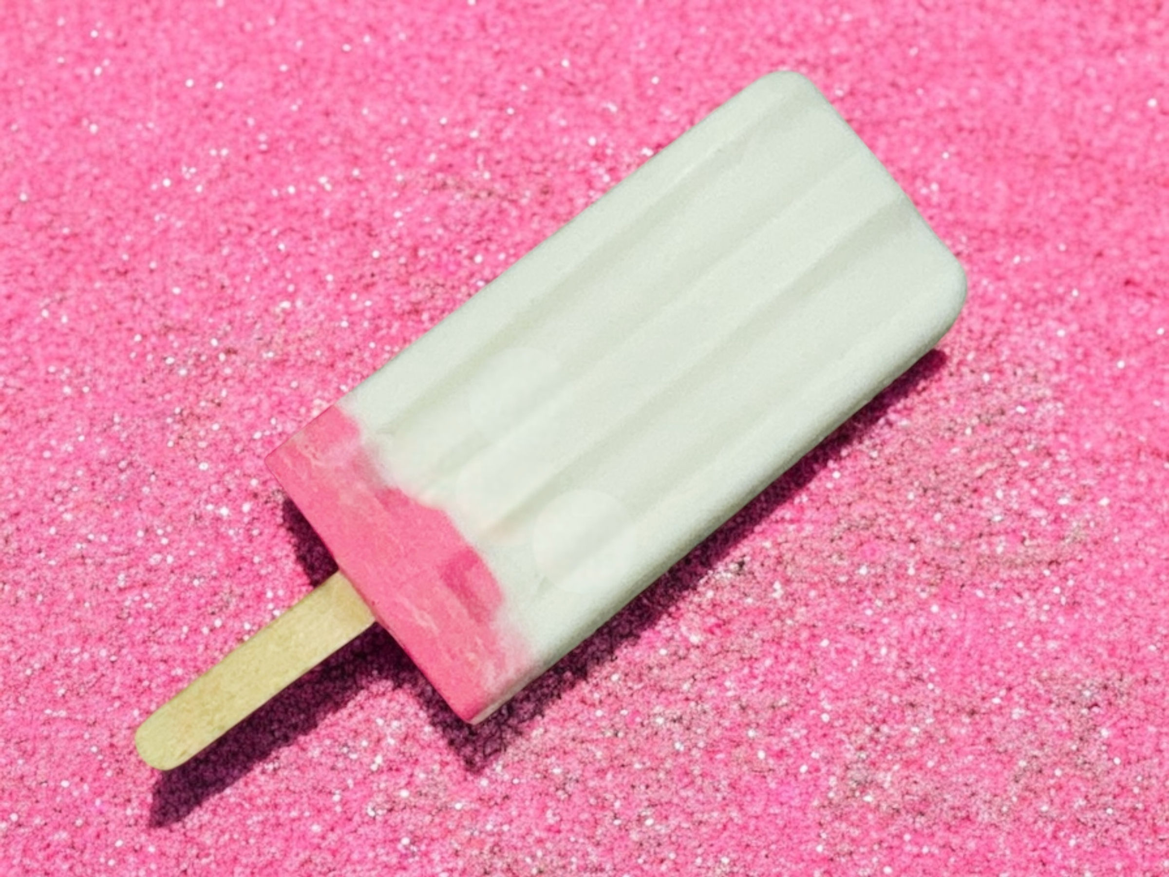 Pink and white popsicle on pink glitter