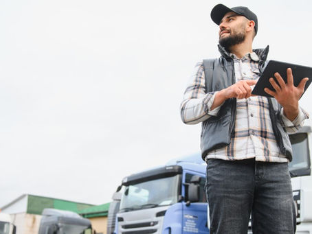 Fleet manager using a tablet beside trucks with Business Central Copilot agents streamlining logistics.