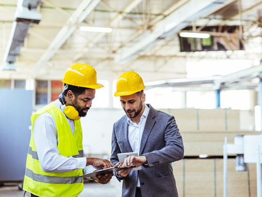 Two factory professionals reviewing tablet data on shop floor, highlighting Business Central features in manufacturing operations