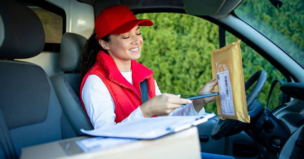 Smiling delivery driver in a red cap scanning a package inside a van, representing real-world logistics supported by a unified ERP for CPG brands, with parcels, clipboard, and green foliage in view.