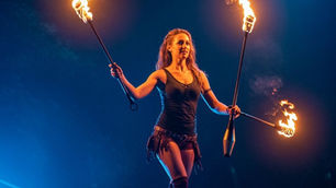 Engaging vs. SEO – A performer balances on a tightrope, holding flaming torches against a dark blue background. The intense, focused mood reflects the challenge of balancing engaging content with SEO strategies.