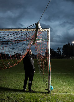 Photographie de portrait d'un entraineur de football, pres des cages de but.