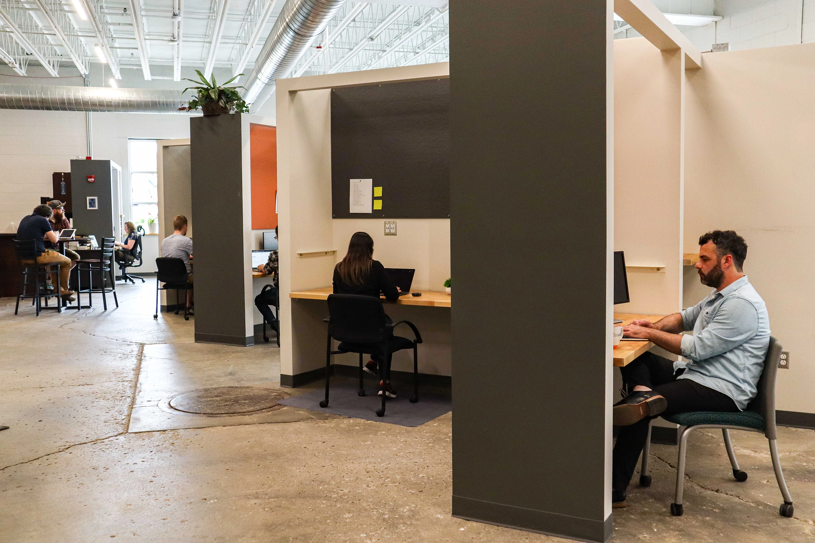 Remote employees and business owners work at desks and tables in the CO:LAB at Madjax